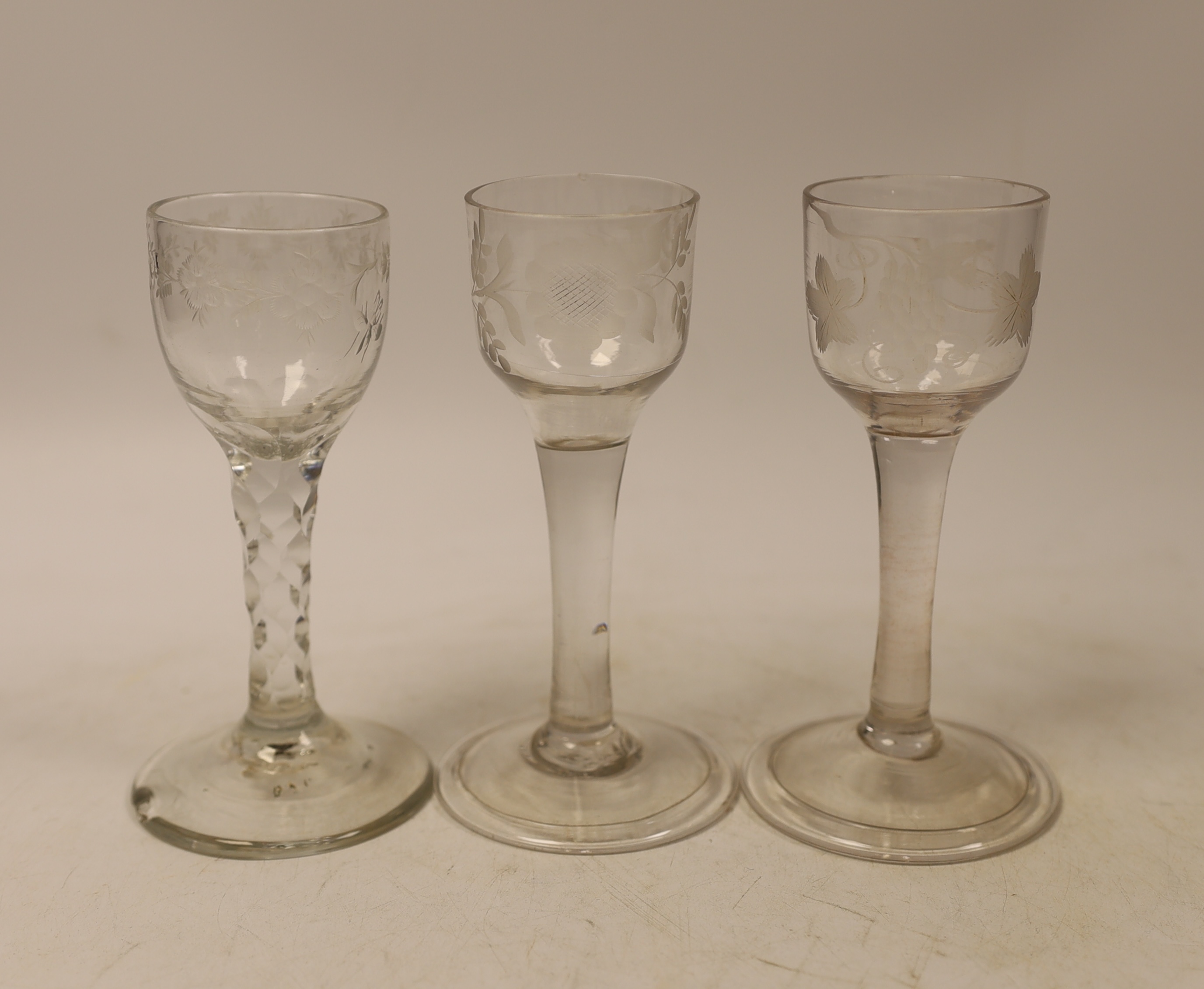 Two mid-18th century cordial glasses, each with wheel engraved decoration to the bowl, on a folded foot, together with a facet stem glass with engraved bowl, c.1780, tallest 13.5cm (3)
